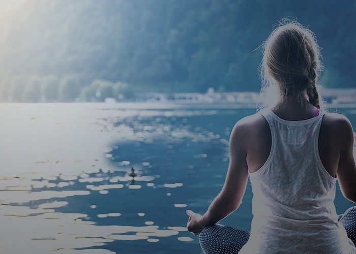 personal development woman meditating facing body of water